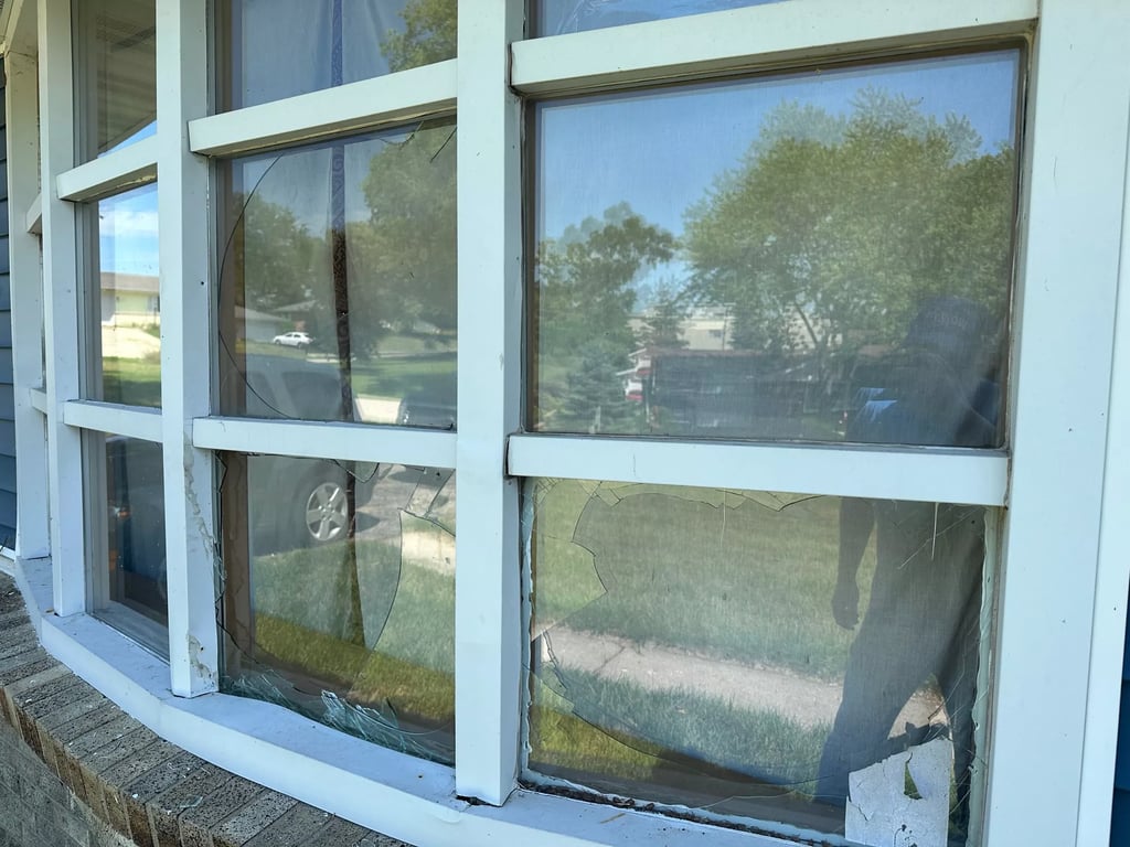 Severely damaged double-pane windows showing crack patterns in commercial window frame, demonstrating need for emergency window repair