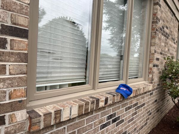 Damaged horizontal window blinds showing curved impact pattern in residential window, demonstrating need for repair