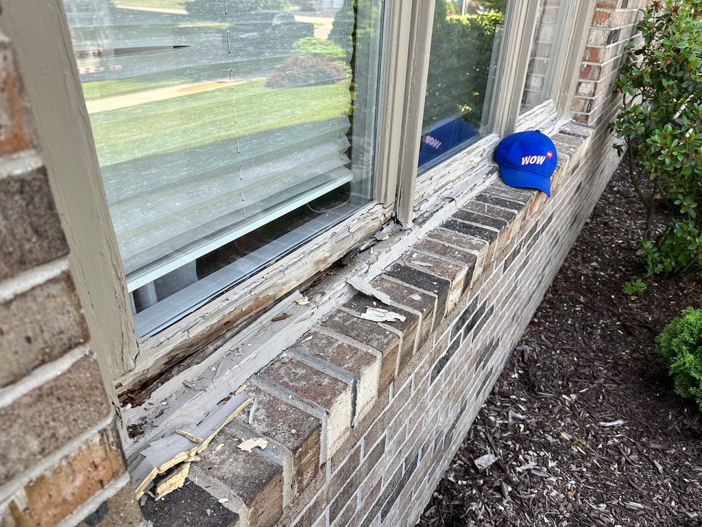 Deteriorating wooden window frame showing severe rot damage on brick home, demonstrating need for professional window repair in Charlotte