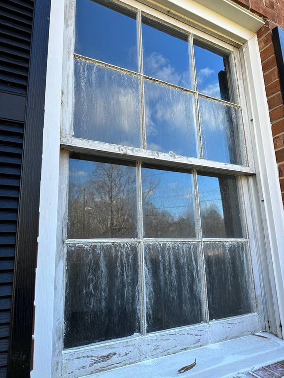 Foggy double-hung window with moisture damage and deteriorating frame, showing common window condensation issues needing repair