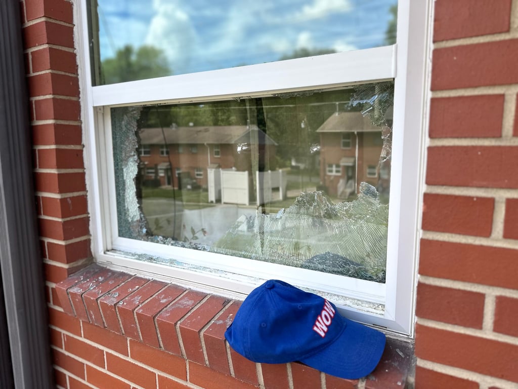 Broken residential window with shattered glass in white frame, showing damage requiring professional window repair in Raleigh