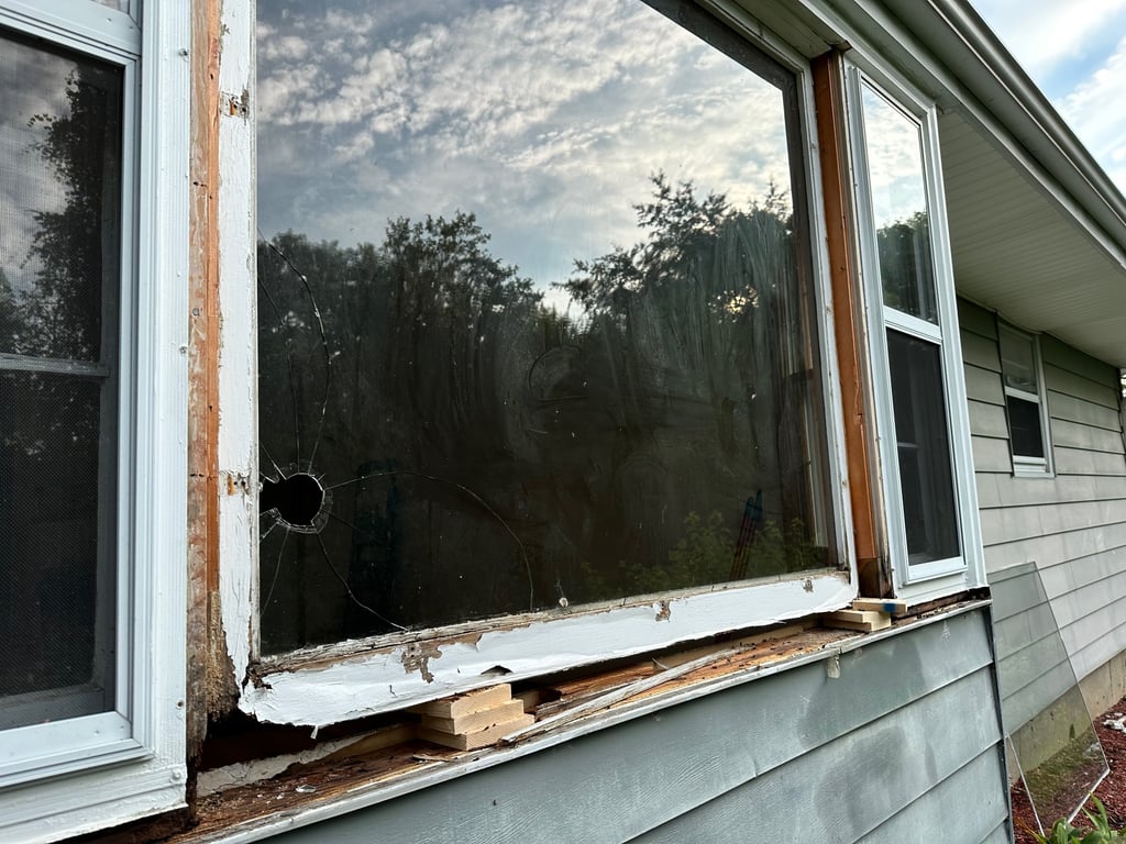 Damaged residential window with broken glass and rotting frame showing severe deterioration, requiring professional window repair in Greensboro