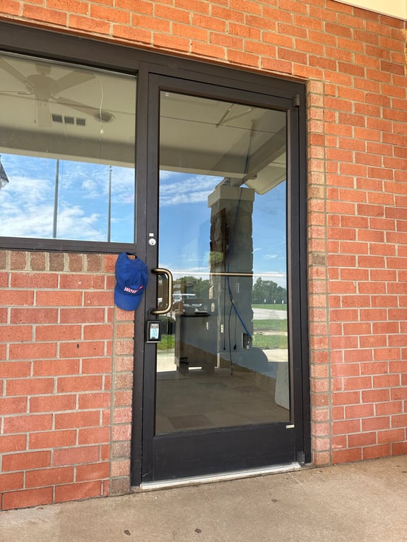 Commercial glass door entrance with WOW branded cap at brick building location in Greensboro Triad Metro area