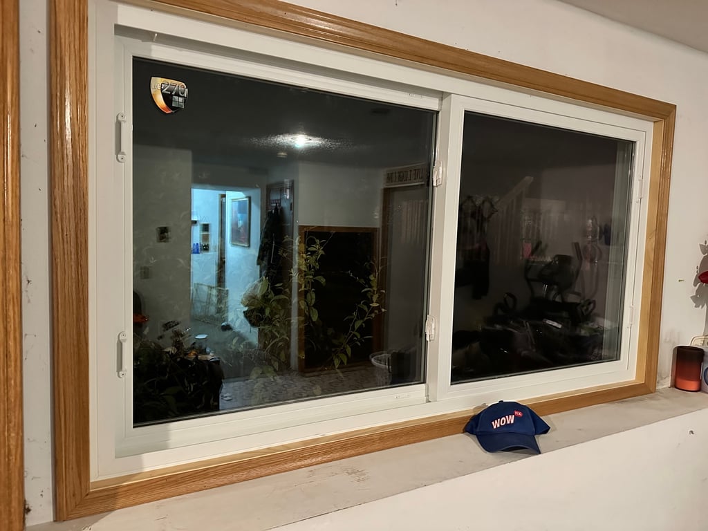 Energy efficient double-pane vinyl window installation with oak trim in Charlotte home, showcasing professional window replacement